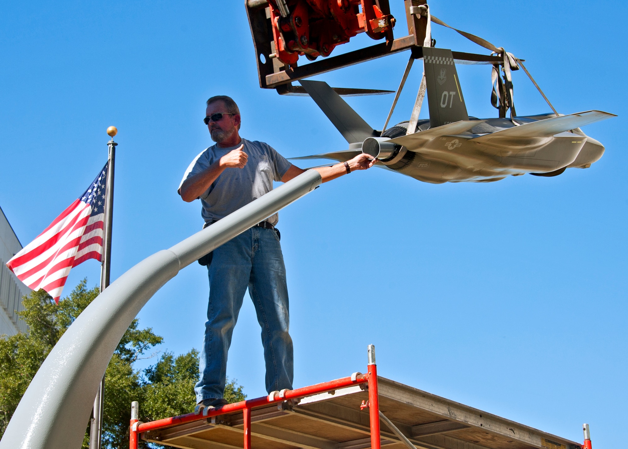 Robert Owens, 796th Civil Engineer Squadron, gives direction to the lift driver while centering up the new F-35 Lightning II static display in front of the 53rd Wing building Nov. 3.  The static display compliments the F-22 display on the left side of the entrance.  The 53rd Wing will be responsible for the operational testing of the F-35 aircraft.  (Air Force photo/ Samuel King Jr.)
