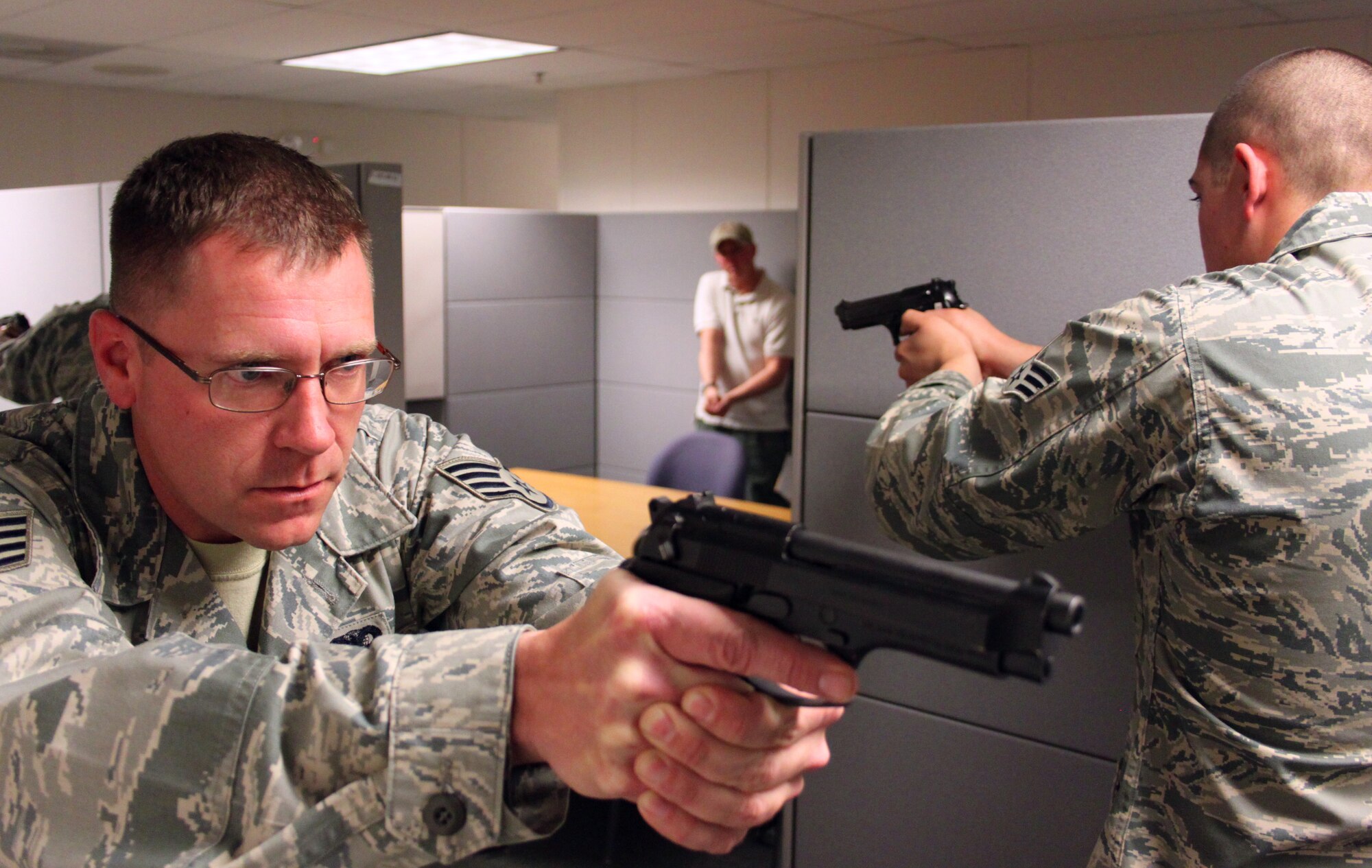 Staff Sgt. Richard Porter, left, clears the 310th Space Wing headquarters building with Senior Airman Matthew Majernik while practicing a three-man scenario during an active shooter exercise on Nov. 7. Shawn O'Reilly, the trainer and the bad guy in the exercises, waits to surprise the advancing security forces Airmen from inside a cubicle. O'Reilly, an ex-Army MP and civilian law enforcement officer at Fort Carson, Colo., worked with members of the security forces squadron on two-man and three-man active shooter scenarios during the unit training assembly. (U.S. Air Force photo/Tech. Sgt. Scott P. Farley)
