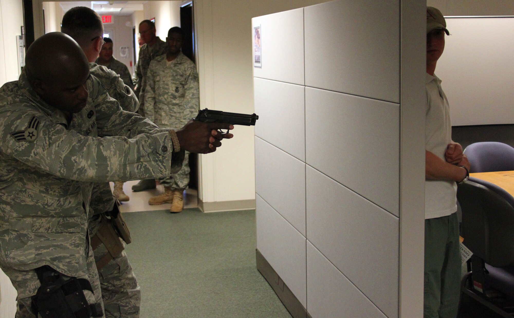 Senior Airman Anthony Glanton, left, clears the 310th Space Wing headquarters building with Senior Airman Arik Leiker trailing behind to protect his back during an active shooter exercise on Nov. 7. Shawn O'Reilly, right, the trainer and the bad guy in the exercise, waits to surprise the advancing security forces Airmen. O'Reilly worked with the members of the security forces squadron on two-man and three-man active shooter scenarios during the unit training assembly. (U.S. Air Force photo/Tech. Sgt. Scott P. Farley)