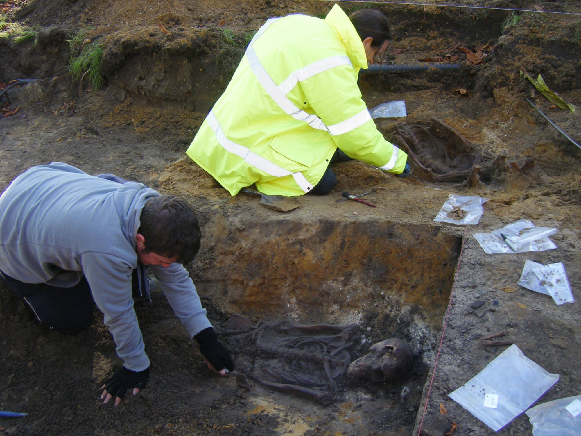 RAF MILDENHALL, England -- Two members of the Suffolk County Council Archaeology Service use trowels, brushes and hand shovels to remove the soil and debris around skeletons found in October 2010 in Washington Square here. Four skeletons have now been found and removed from the area, and have been taken to Bury St. Edmunds before being sent to a bone specialist in Scotland. (Courtesy photo/Suffolk County Council Archaeological Service)