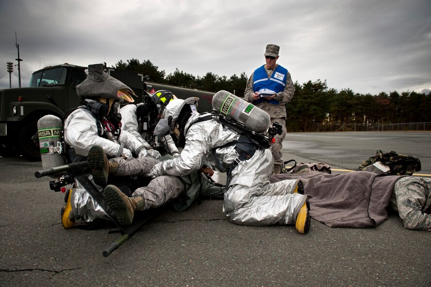 Members of the 35th Civil Engineer Squadron fire department roll a simulated attack casualty onto a stretcher during an operational readiness exercise at Misawa Air Base, Japan, Nov. 9, 2010. The fire department responded in concert with the 35th Logistics Readiness Squadron to manage a simulated fuel spill and simulated injured victims. (U.S. Air Force photo by Staff Sgt. Samuel Morse/Released)