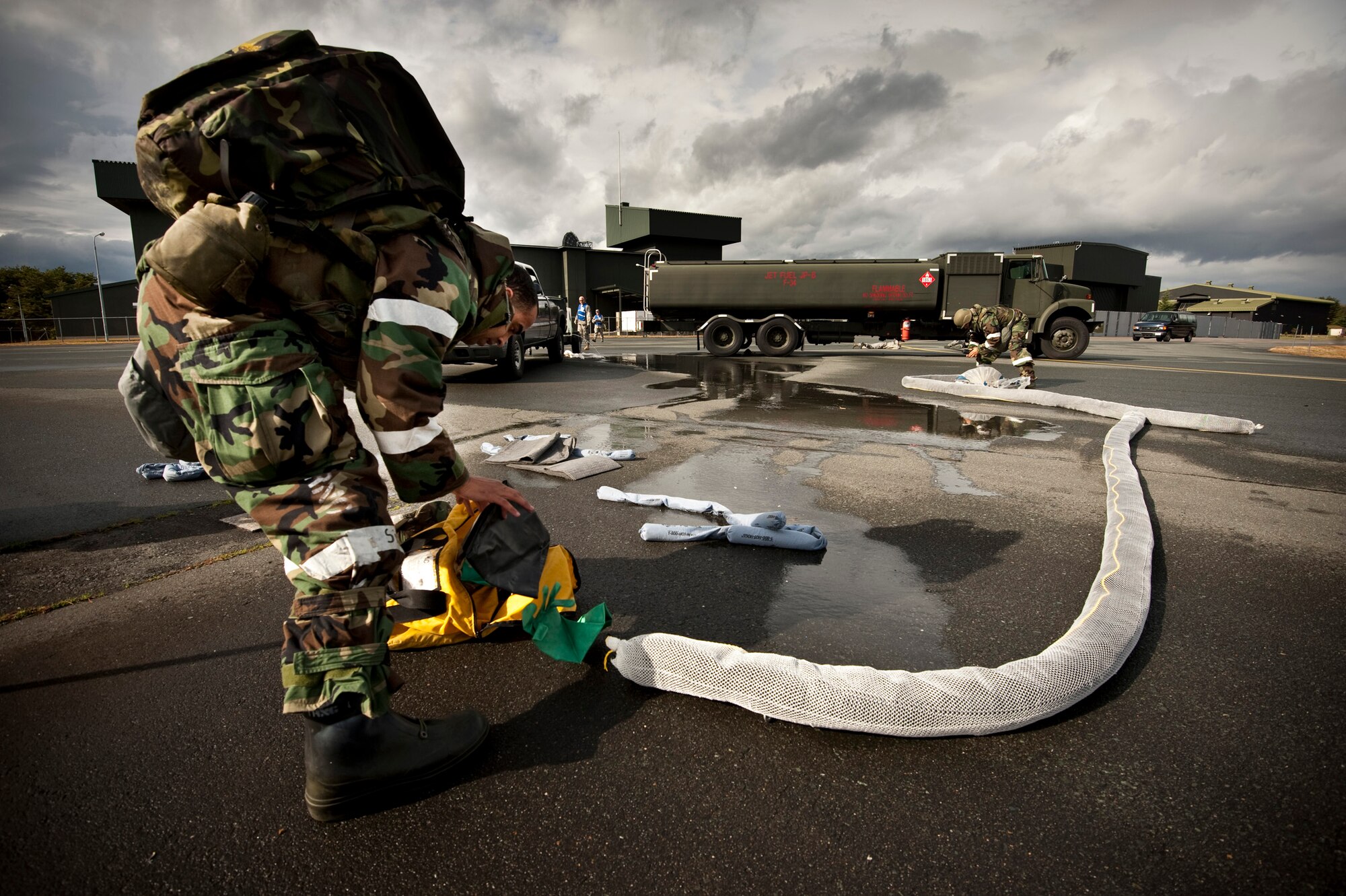 U.S. Air Force Staff Sgt. Joshua Eisenman, 35th Logistics Readiness Squadron fuels expediter, grabs protective gloves to help contain a simulated JP-8 fuel leak from an R-11 Refueler during an operational readiness exercise at Misawa Air Base, Japan, Nov. 9, 2010. The exercise evaluation team dumped water to help the responders visualize the simulated class three spill of approximately 600 gallons of fuel. (U.S. Air Force photo by Staff Sgt. Samuel Morse/Released)