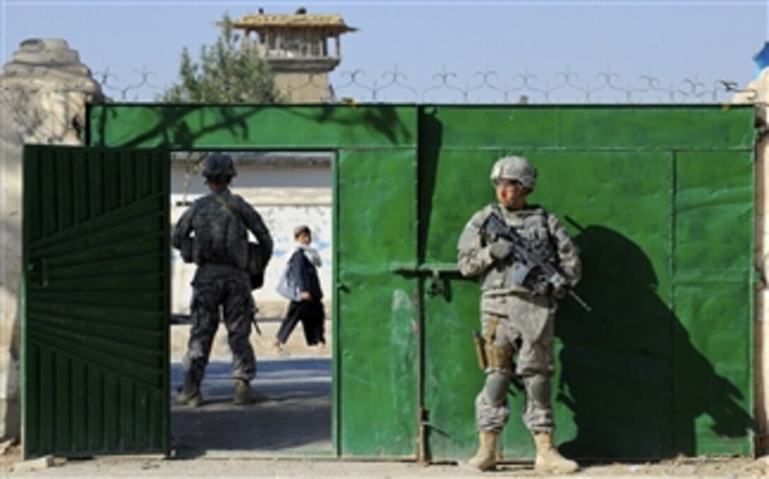 U.S. Army Pfcs. Nicholas Sudano (right) and Nicholas Querzoli, both assigned to the Zabul Provincial Reconstruction Team, secure the gate to the construction site of a radio station and media center while engineers inspect the project site in Qalat, Afghanistan, on Nov. 6, 2010.  