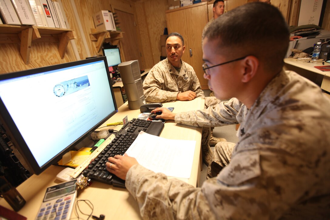 Petty Officer 1st Class Darlito Gacuya, a Navy personnel officer with G-1, Headquarters, 1st Marine Logistics Group (Forward), assists Petty Officer 2nd Class Paul Gomez, the command master chief’s assistant, Headquarters, 1st MLG (FWD), in making sure he is getting paid correctly, Nov. 9. The G-1’s responsibilities include Marine and sailor accountability, basic administrative assistance, casualty tracking, notification of red-cross messages, and scheduling of emergency leave and rest and recuperation leave.