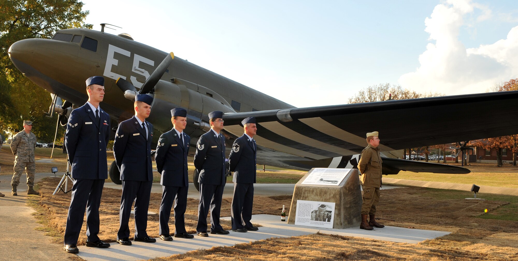Randall Watts (right), representing a World War II paratrooper, stands at parade rest while members of the renovation team stand behind him during the aircraft’s christening at the Veterans Day retreat ceremony at Heritage Park Nov. 10. Team Little Rock Airmen worked for months repairing and repainting the C-47 Skytrain to match its June 1944 D-Day paint scheme. (U.S. Air Force photo by Senior Airman Gul Crockett)