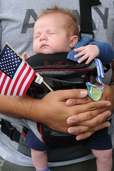 An Army captain proudly embraces his newborn son and an American flag while the infant sleeps during the 2010 Big Island Veterans Day Parade in Hilo, Hawaii, Nov. 6, 2010. (U.S. Air Force photo/Tech. Sgt. Jerome S. Tayborn)
