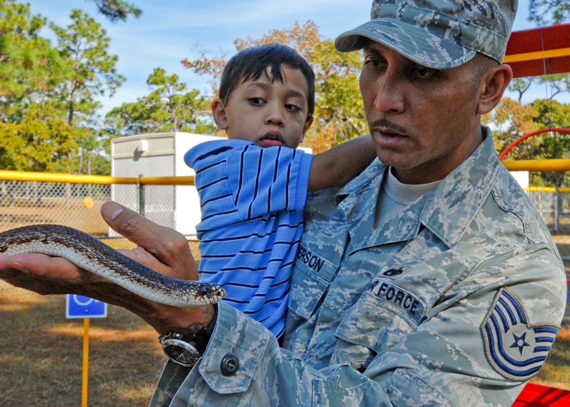 Tech. Sgt. Timothy Anderson, 33rd Fighter Wing, holds his apprehensive 2-year-old son Mateo as he holds a snake at the Child Development Center Fall Festival Nov.10. The annual festival celebrated the Month of Military Families. (U.S. Air Force photo/Sachel Seabrook)

