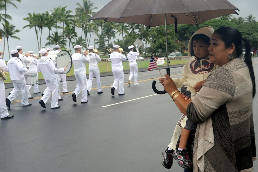 A mother and her small child proudly wave an American flag, despite the rain, as the Naval Pacific Fleet Band performs during the 2010 Big Island Veterans Day Parade in Hilo, Hawaii, Nov. 6, 2010. City officials invited the National Security Agency/Central Security Service Joint Service Color Guard and the Naval Pacific Fleet Band to participate in the parade that day. (U.S. Air Force photo/Tech. Sgt. Jerome S. Tayborn)
