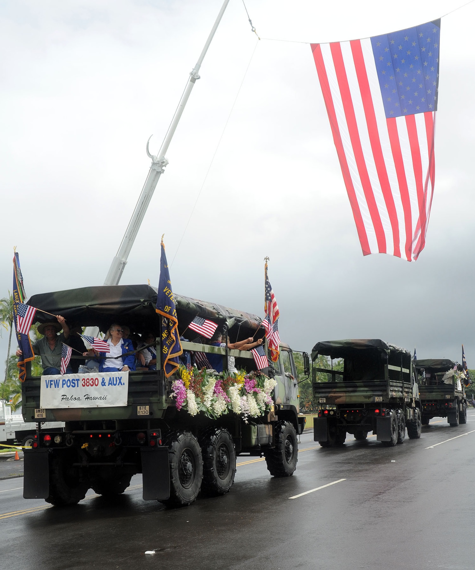 Decorated military trucks carrying veterans pass by a draped American flag during the 2010 Big Island Veterans Day Parade in Hilo, Hawaii, Nov 6. 2010. (U.S. Air Force photo/Tech. Sgt. Jerome S. Tayborn)