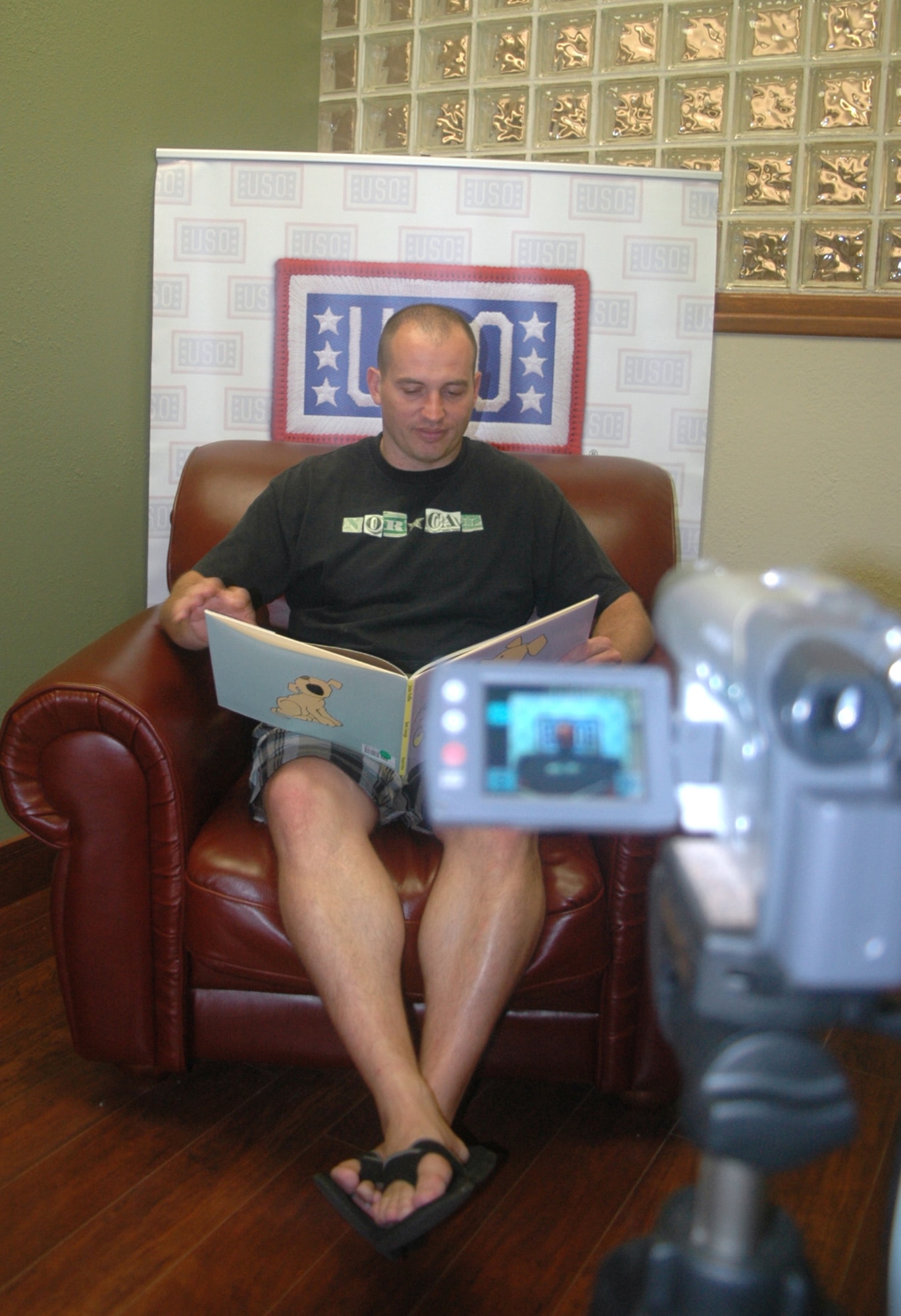 Tech. Sgt. David Aceveda, a member of the 744th Communications Squadron, Joint Base Andrews Naval Air Facility, Md., and spouse of Master Sgt. Veronica Aceveda, 512th Airlift Wing, reads a children's book in front of a video camera Sept. 24 inside the USO Community Center on Dover Air Force Base, Del., as part of the United Through Reading program. While Sergeant Aceveda is deployed, the pre-recorded DVD and book will be sent to his children for free. (U.S. Air Force photo by Tech. Sgt. Scott Farley/Released)