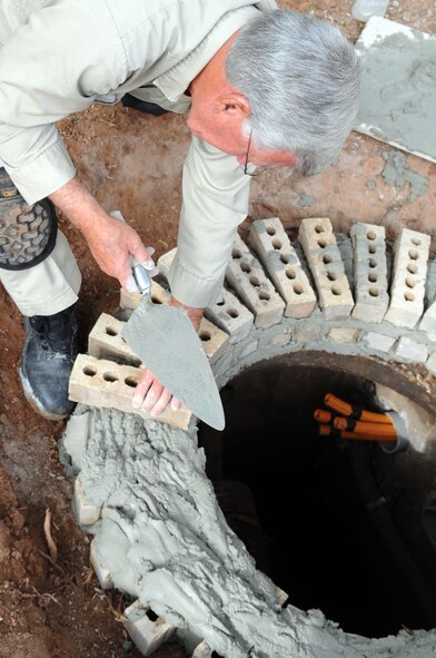 Glynn Stephens, 2nd Civil Engineer Squadron, masonry specialist, raise a manhole to element groundwater from running into it at Barksdale Air Force Base, La., Nov 9. The 2 CES provides fire protection, readiness training and emergency management support, explosive ordnance disposal and environmental protection of land, air and water. (U.S. Air Force photo/Senior Airman Brittany Y. Bateman)(RELEASED)