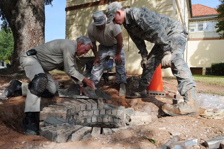 Members of the 2nd Engineer Squadron, use bricks to raise a manhole at Barksdale Air Force Base, La., Nov. 9. The purpose of the construction is to eliminate groundwater from running into it. The 2 CES provides fire protection, readiness training and emergency management support, explosive ordnance disposal and environmental protection of land, air and water. (U.S. Air Force photo/Senior Airman Brittany Y. Bateman)(RELEASED)