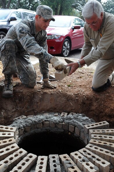 Airman 1st Class Rickey George, 2nd Civil Engineering Squadron, structural engineer, and Glynn Stephens masonry specialist, raises a manhole to eliminate groundwater from running into it at Barksdale Air Force Base, La., Nov 9. The 2 CES combines the talent of nearly 400 military and civilian members, who build, operate, maintain and protect $2.8 billion in real property. (U.S. Air Force photo/Senior Airman Brittany Y. Bateman)(RELEASED)