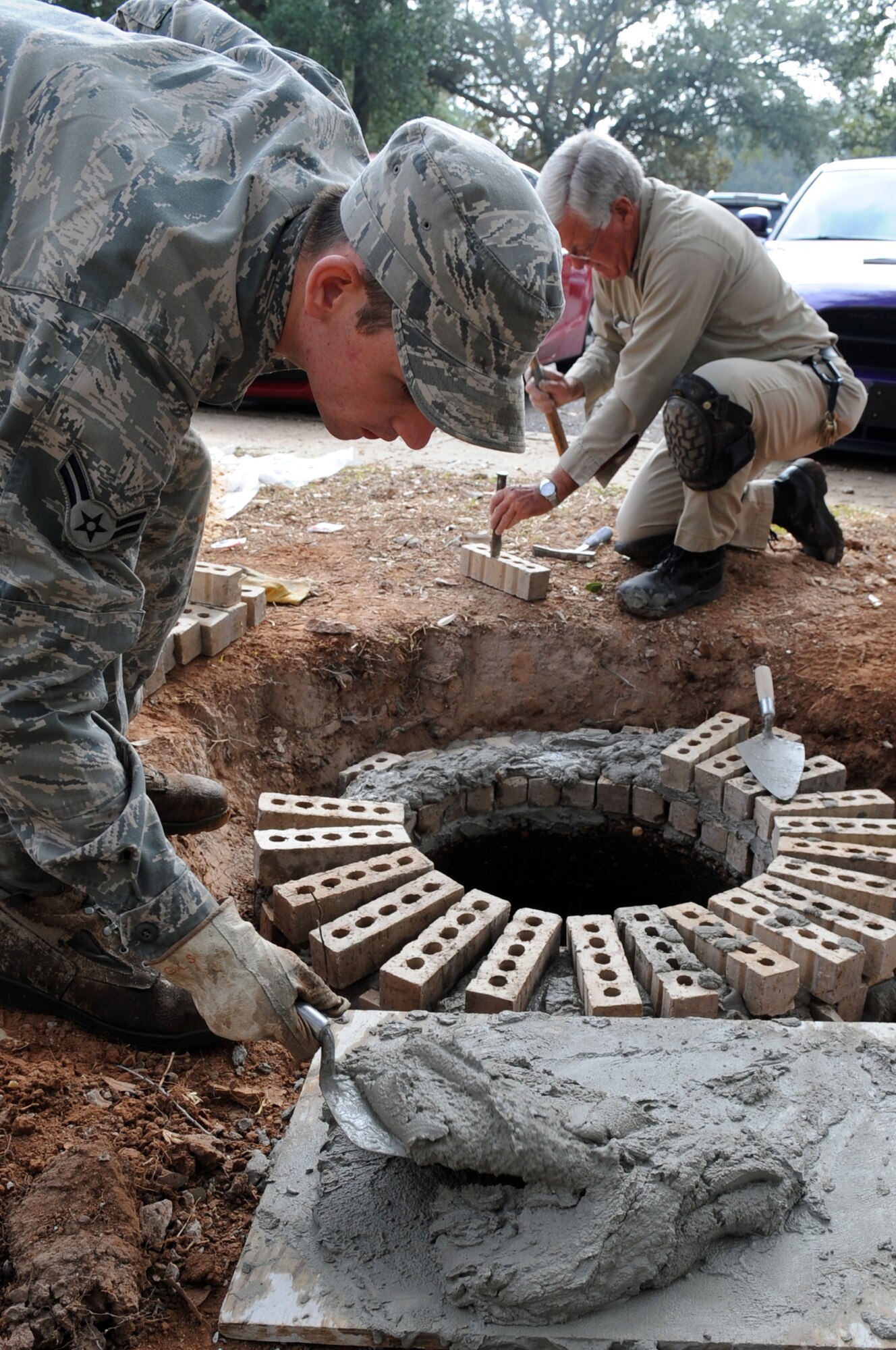Airman 1st Class Rickey George, 2nd Civil Engineering Squadron, structural engineer, and Glynn Stephens masonry specialist, raise a manhole to eliminate groundwater from running into it at Barksdale Air Force Base, La., Nov 9. The 2 CES combines the talent of nearly 400 military and civilian members, who build, operate, maintain and protect $2.8 billion in real property. (U.S. Air Force photo/Senior Airman Brittany Y. Bateman)(RELEASED) 