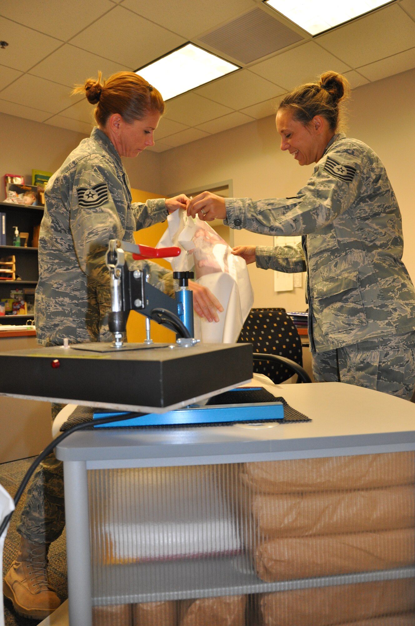 WRIGHT-PATTERSON AIR FORCE BASE, Ohio - Tech. Sgts. Heather Chapman and Natalie Storms, 445th Airman and Family Readiness office, remove transfer paper from a pillow case after printing the photo of a deployed Airman on it. (U.S. Air Force photo/Staff Sgt. Amanda Duncan)