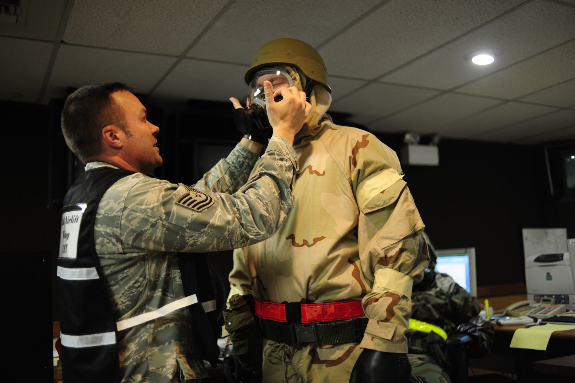 Tech. Sgt. Ray Smittle, left, 62nd Airlift Wing Command Post, inspects the mask of  Staff Sgt. Jared Payne, 62nd AW CP, as part of his personal protective equipment during the MOBEX Nov. 8 at McChord Field, Joint Base Lewis-McChord, Wash. (U.S. Air Force photo/Amn Leah Young)