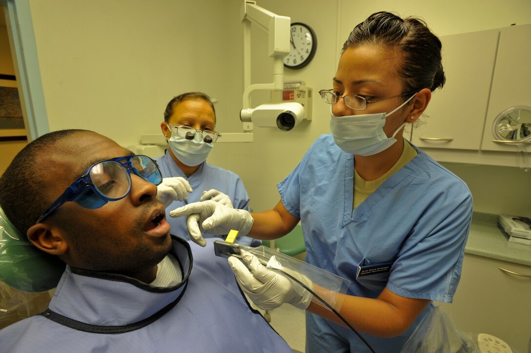 Airman 1st Class Iris Silva-Arteaga, 779th dental technician, places a digital sensor inside the mouth of Airman 1st Class Marcus Primer, 779th dental technician during a routine checkup, as Maj. Cynthia Hernandez-Falu, 779th dentist observes. (U.S. Air Force photo/Bobby Jones)