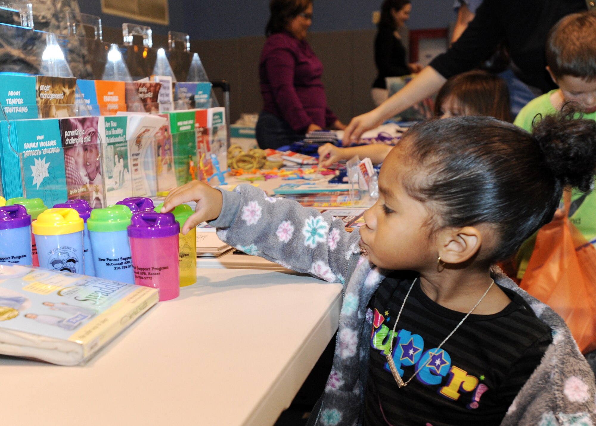 Michaela Davis, 2, reaches for a cup offered from McConnell’s Family Advocacy Program table during the annual Family Fun and Feast night, Nov. 9, 2010, McConnell Air Force Base, Kan.  The two-hour event provided hamburgers, hotdogs, drinks, snacks and activities for Team McConnell families.  More than 375 people attended the event.  (U.S. Air Force photo/Airman 1st Class Andrea Salazar)
