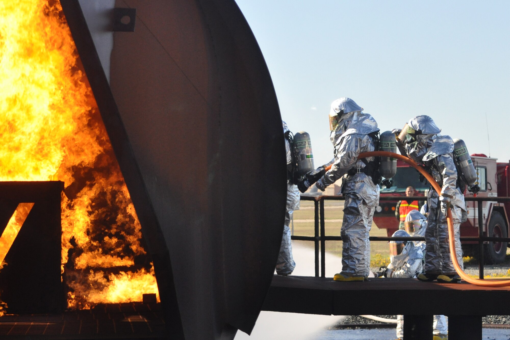 Col. John J. Mooney III, commander, 917th Wing, at the nozzle, leads a team of 917th Civil Engineer Squadron firefighters into a burning wall of propane flames in an aircraft trainer at Barksdale Air Force Base, La., Nov. 5, 2010. Colonel Mooney decided to take up the challenge, in order to experience and get a feel for what Airmen in his command go through on a daily basis. He joined approximately 20 members of the 917 CES in this phase of wartime training, which included the extinguishing of a fire on a large frame aircraft trainer. For the professional firefighters, it was a part of their annual Air Force Certification process for Airport Rescue Firefighting.  (U.S. Air Force photo/Tech. Sgt. Jeff Walston) 