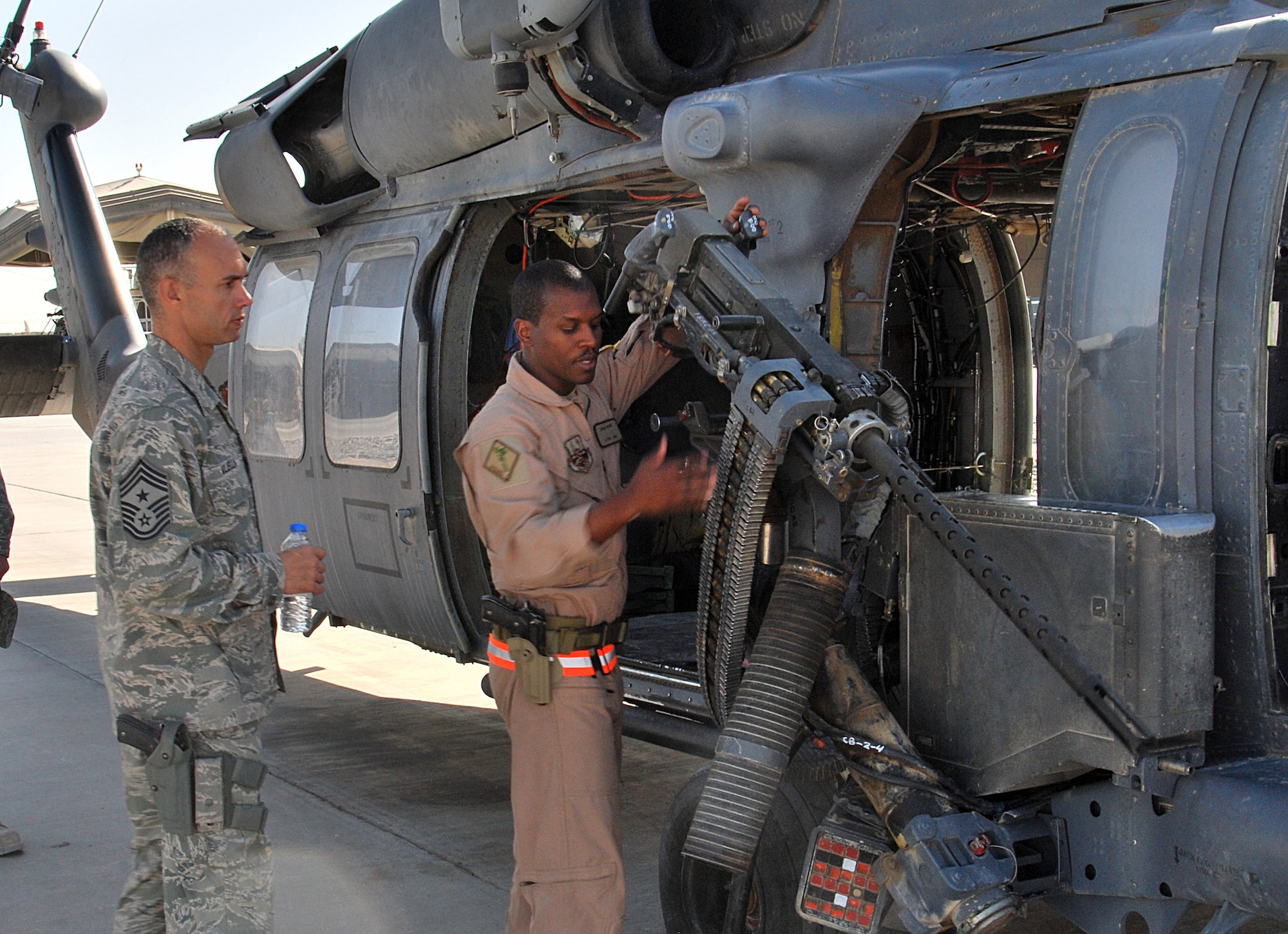 Tech. Sgt. Mark Moore shows off some features of the HH-60 Pave Hawk to Chief Master Sgt. Mark Villella during his visit to Kandahar Airfield, Afghanistan, Nov. 7. Sergeant Moore is with the 26th Expeditionary Rescue Squadron, and Chief Villella is the Air Force Central Command chief. (U.S. Air Force photo by Senior Airman Melissa B. White/Released)