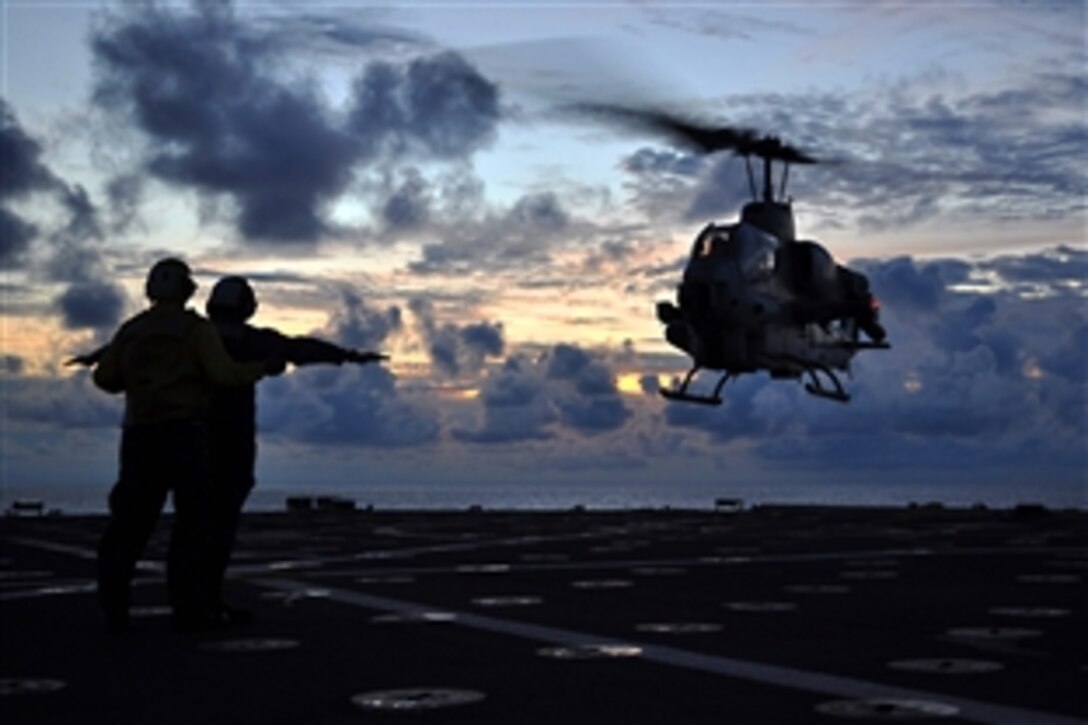 U.S. Navy Petty Officer Adam Pond, left, assists Petty Officer Norberto Riegodedios, right, during the recovery of an AH-1W Cobra helicopter aboard the amphibious transport dock ship USS Denver in the South China Sea, Nov. 9, 2010. 