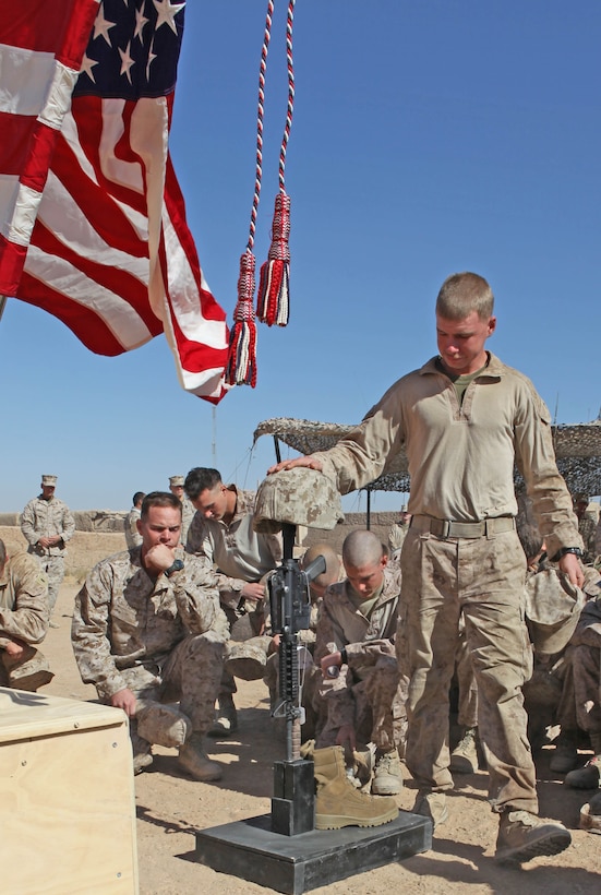 Marines with 2nd Battalion, 9th Marine Regiment, pay their respect in front of a battlefield cross display honoring Lance Cpl. Terry E. Honeycutt Jr., a machine-gunner with Fox Company,2/9, during a memorial service at a Marine Corps Base in Helmand Province, Afghanistan, Nov. 11. Honeycutt gave the ultimate sacrifice, Oct. 27, while conducting combat operations in Northern Marjah.