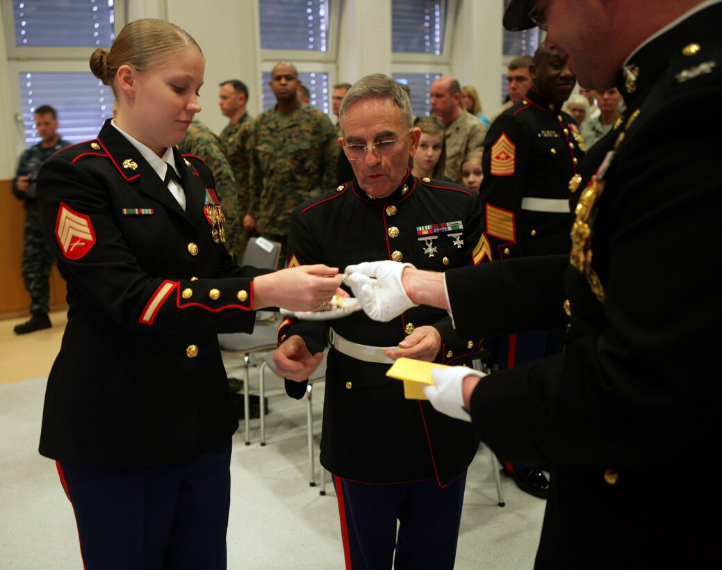 The oldest Marine present, Cpl. Truman Goodwin and the youngest Marine, Sgt. Christine Bloomfield, adjutant clerk for U.S. Marine Corps Forces Europe accept a piece of cake from Col. Adam J. Copp, chief of staff for U.S. Marine Corps Forces Europe. Cpl. Goodwin served in the Marine Corps from January 1955 to January 1961. U.S. Marine Corps Forces Europe Marines travelled from Stuttgart to celebrate the Marine Corps Birthday with wounded Marines and Marines serving at the Marine Corps Liaison Det.