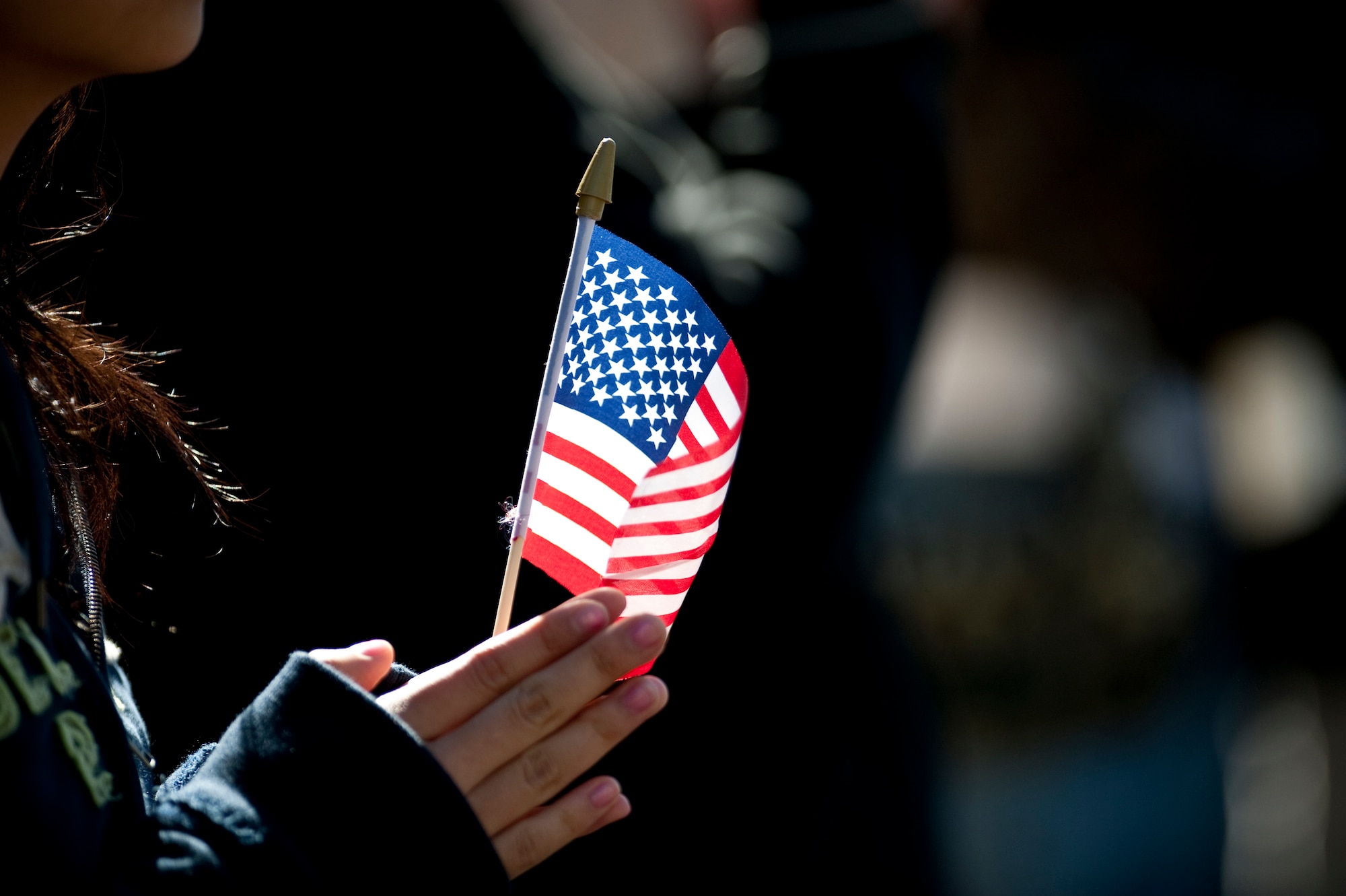 LAS VEGAS -- A spectator hold an American Flag while Airmen from the U.S. Air Force Honor Guard march and perform during the Las Vegas Veterans Day Parade Nov. 11, 2010. Airmen from Nellis Air Force Base, Nev., Airman Leadership School also participated in the parade.  (U.S. Air Force photo / Tech. Sgt. Michael R. Holzworth)(Released)