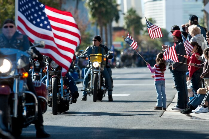 LAS VEGAS -- Spectators waive American flags as members of the  Las Vegas Veterans of Foreign Wars motorcycle riders pass by during the Las Vegas Veterans Day parade Nov. 11, 2010. Airmen from the U.S. Air Force Honor Guard and Nellis Air Force Base participated in the parade.  (U.S. Air Force photo / Tech. Sgt. Michael R. Holzworth)(Released)