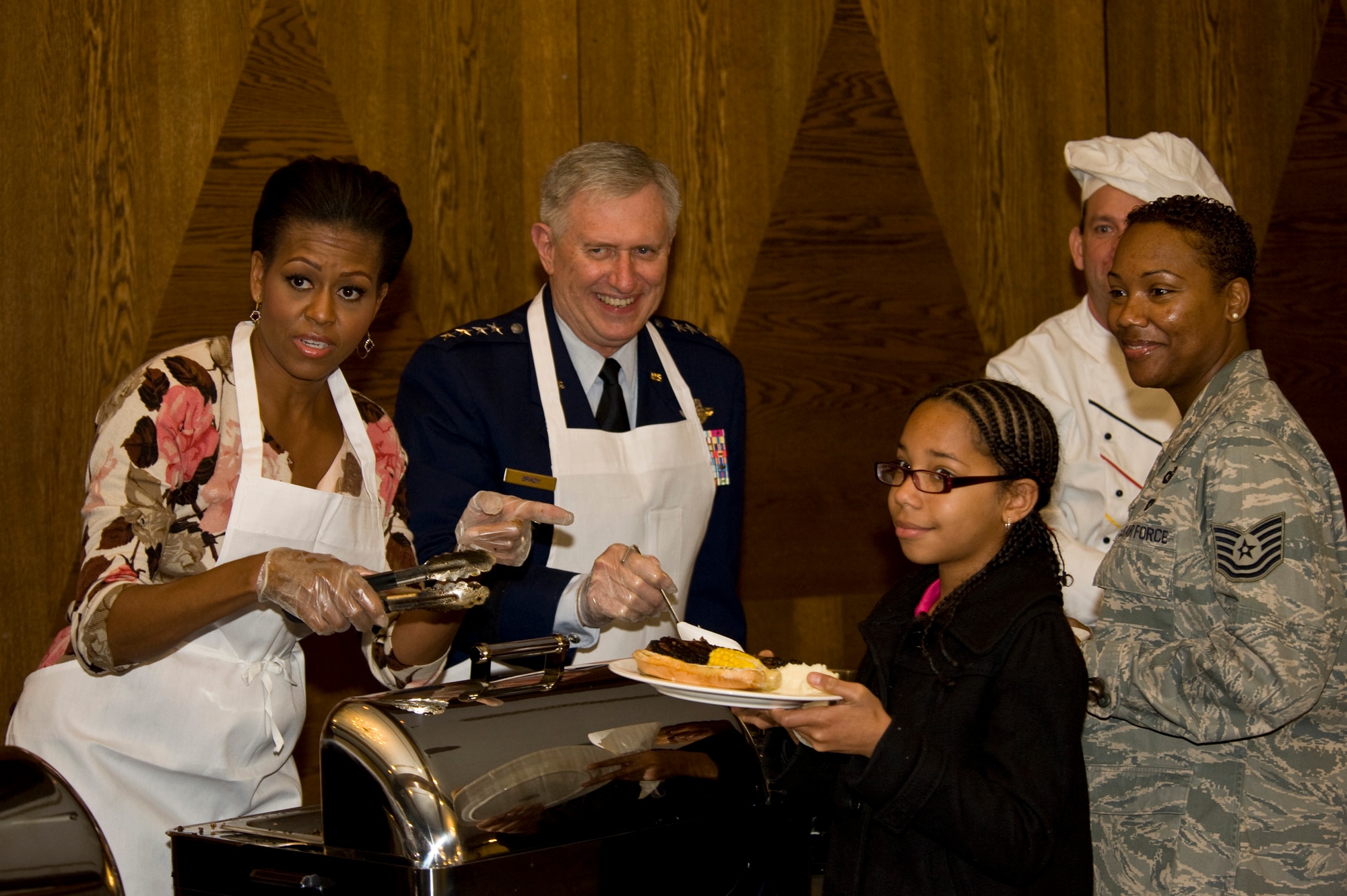 First Lady Michelle Obama and Gen. Roger A. Brady, U.S. Air Forces in Europe commander, ask the press pool if they want a dinner plate while serving military members and their families at the Officers Club at Ramstein Air Base, Germany, Nov. 11, 2010. The First Lady made a surprise visit to Ramstein during her return from a nine-day tour of Asia to show her support for servicemembers and their families during this Veterans Day. She met with wounded servicemembers at Landstuhl Regional Medical Center, served lunch, talked briefly to the servicemembers and families and met with German first lady Bettina Wulff before flying on to the United States. (U.S. Air Force photo/Tech. Sgt. Wayne Clark) 