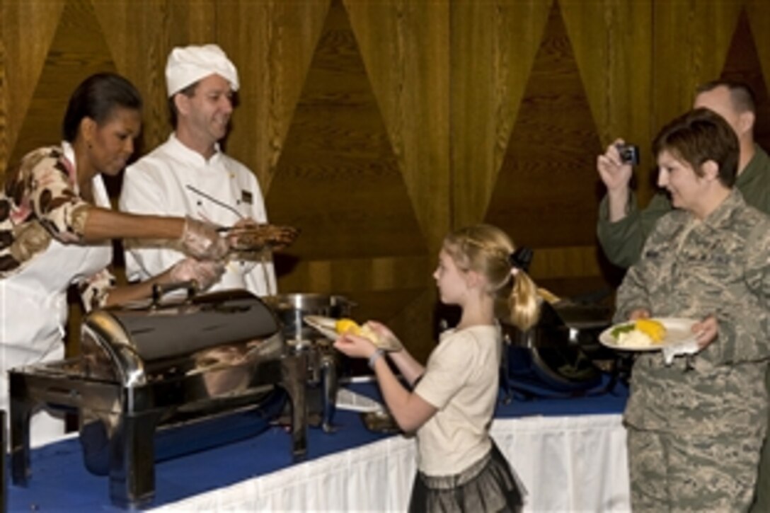 First Lady Michelle Obama serves steak to 8-year-old Paris Binard while her parents Air Force Tech. Sgt. Kristi Binard and Senior Airman Rob Binard look on during a Veterans Day dinner on Ramstein Air Base, Germany, Nov. 11, 2010. The first lady made a surprise visit to Ramstein during her return from a nine-day tour of Asia.