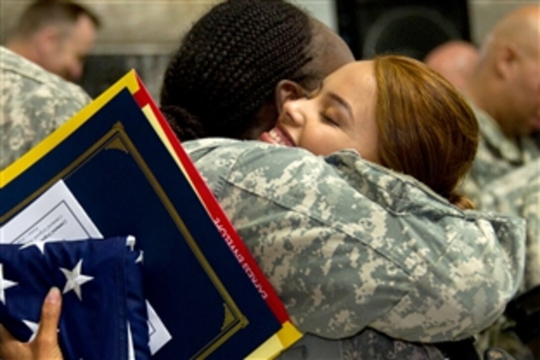 U.S. Army Spc. Jehan Custodio Martinez receives a hug after becoming a U.S. citizen during a naturalization ceremony on Veterans Day in the Al Faw Palace on Camp Victory, Iraq, Nov. 11, 2010. United States Forces-Iraq hosted the ceremony in which 50 troops took the Oath of Allegiance and became citizens.