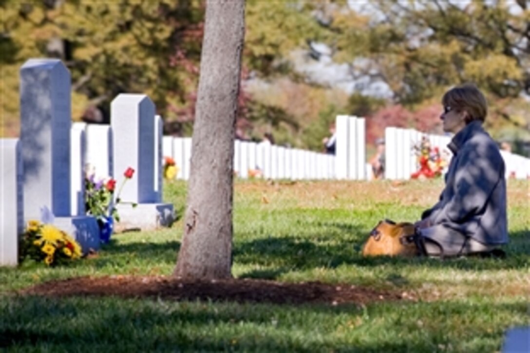 A woman sits quietly at a loved one's gravesite on Veterans Day at Arlington National Cemetery in Arlington, Va., Nov. 11, 2010.