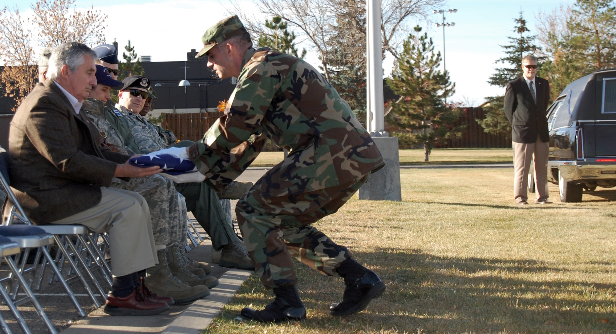 2nd Lt. Brian Quinlan, 12th Missile Squadron, ICBM deputy combat crew commander, passes the flag to Michael Winters, Mayor of Great Falls, during a full-honor funeral demonstration Nov. 5 at Medal of Honor Park. During a real funeral, attendees stand and ceremonial guardsmen are dressed in ceremonial uniforms. (U.S. Air Force photo/Staff Sgt. Dillon White)