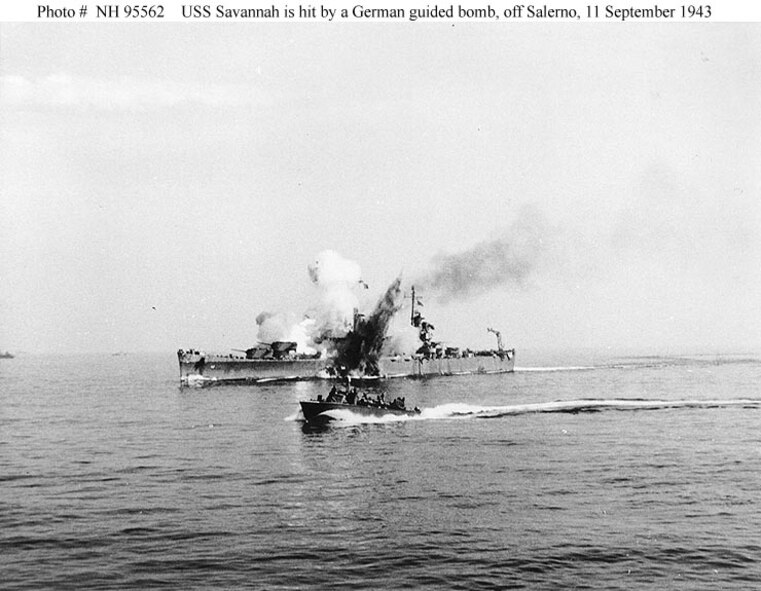 The U.S.S. Savannah is hit by a German radio-controlled bomb, while supporting Allied forces ashore during the Salerno operation, September 11, 1943. The bomb hit the top of the ship's number three 6"/47 gun turret and penetrated deep into her hull before exploding. The photograph shows the explosion venting through the top of the turret and also through Savannah's hull below the waterline. A motor torpedo boat (PT) is passing by in the foreground.(Courtesy of the Naval Historical Foundation. Collection of Admiral H. Kent Hewett, USN. U.S. Naval Historical Center Photograph.)