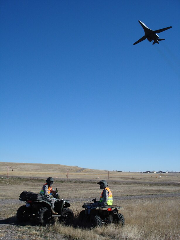ELLSWORTH AIR FORCE BASE, S.D. - A B-1B Lancer flies above Col. Trent Edwards, 28th Mission Support Group commander and Col. Jeffrey Taliaferro, 28th Bomb Wing commander while they perform a perimeter check with 28th Security Forces Squadron Airmen. The SFS Airmen perform the checks regularly to ensure the integrity of the base perimeter. (Courtesy photo/Master Sgt. Carlos Moore)