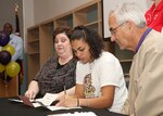 Stacey senior Cordia Harvatin signs a letter of intent to attend Southwestern Assemblies of God University next year as mom, April, and SAGU women's basketball coach Arlon Beadle watch on, Nov. 5 at the Lyon Center on the high school campus. (U.S. Air Force photo/Robbin Cresswell)