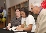 Stacey senior Cordia Harvatin signs a letter of intent to attend Southwestern Assemblies of God University next year as mom, April, and SAGU women's basketball coach Arlon Beadle watch on, Nov. 5 at the Lyon Center on the high school campus. (U.S. Air Force photo/Robbin Cresswell)