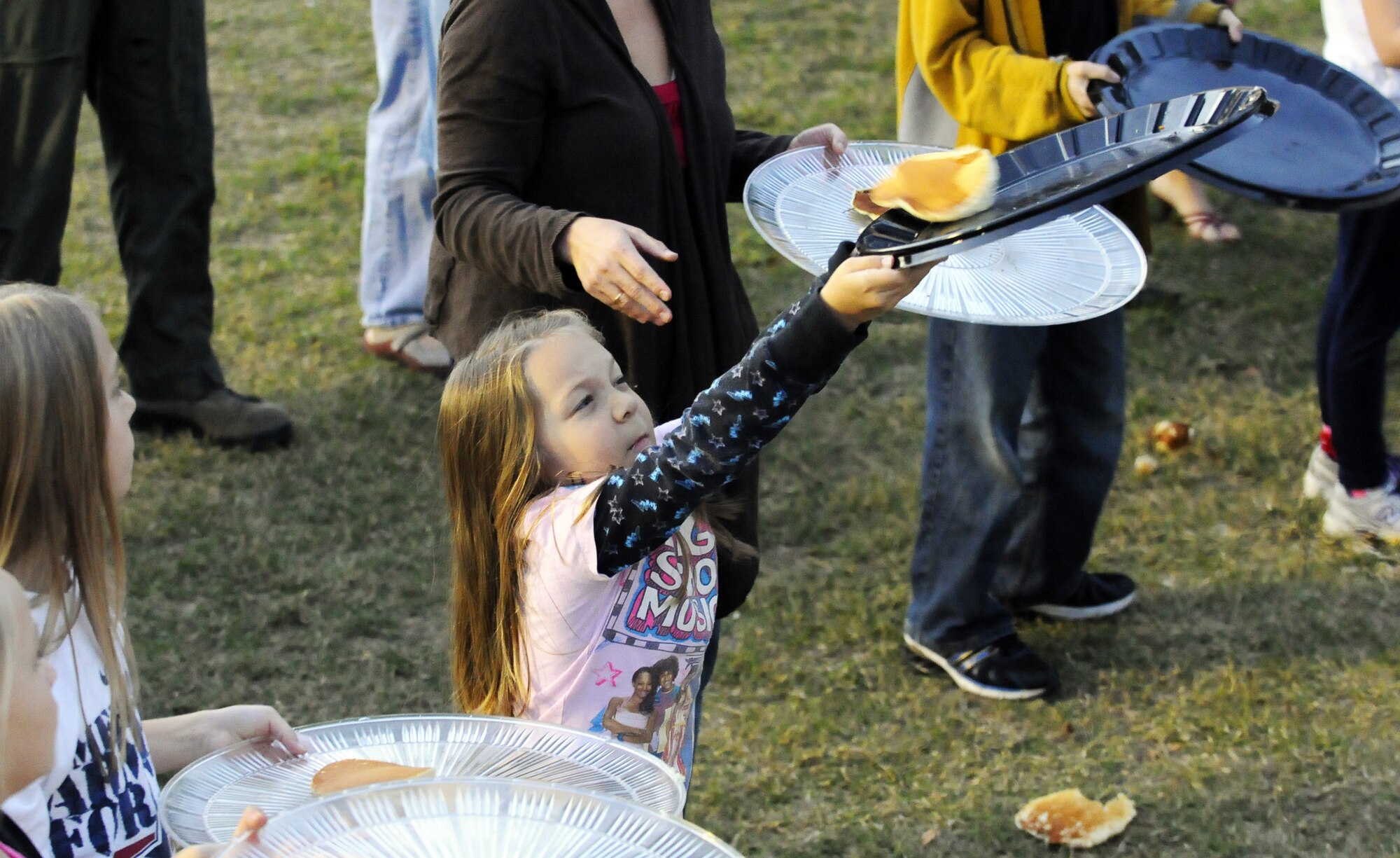Julia Bruce, 6, reaches high to catch a pancake. U. S. Air Force photo by Sue Sapp