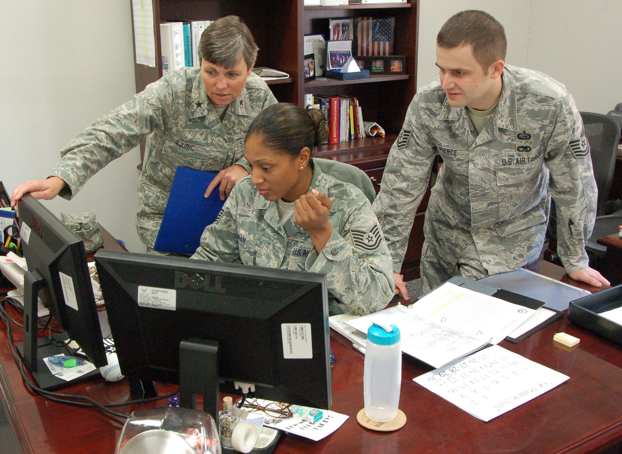 Brig Gen. Teresa Djuric, former Holm Center commander, Tech. Sgt. Renika Kenan, NCOIC, executive services, Holm Center, and Tech. Sgt. Damien Pierce, executive assistant, Holm Center, team up to solve an Officer Training School-related issue last month. (Air Force Photo/Airman 1st Class Christopher S. Stoltz)