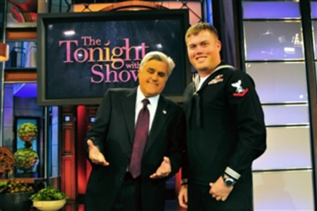 U.S. Navy Petty Officer 3rd Class Joshua Nistas, assigned to the aircraft carrier USS Carl Vinson, poses with Jay Leno, host of The Tonight Show, after a filming of the show on Veterans Day, Burbank, Calif., Nov. 11, 2010.