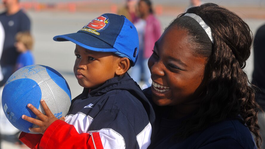 MOODY AIR FORCE BASE, Ga. -- Jessica Hollis holds her brother Jartavious Fulton while attempting to make the ball in the hoop at the Community Appreciation Day Air Show Nov. 13. The Air Show had a number of family oriented activities to do while community members waited for the start of the Air Show. (U.S. Air Force photo/Airman 1st Class Joshua Green)(RELEASED)
