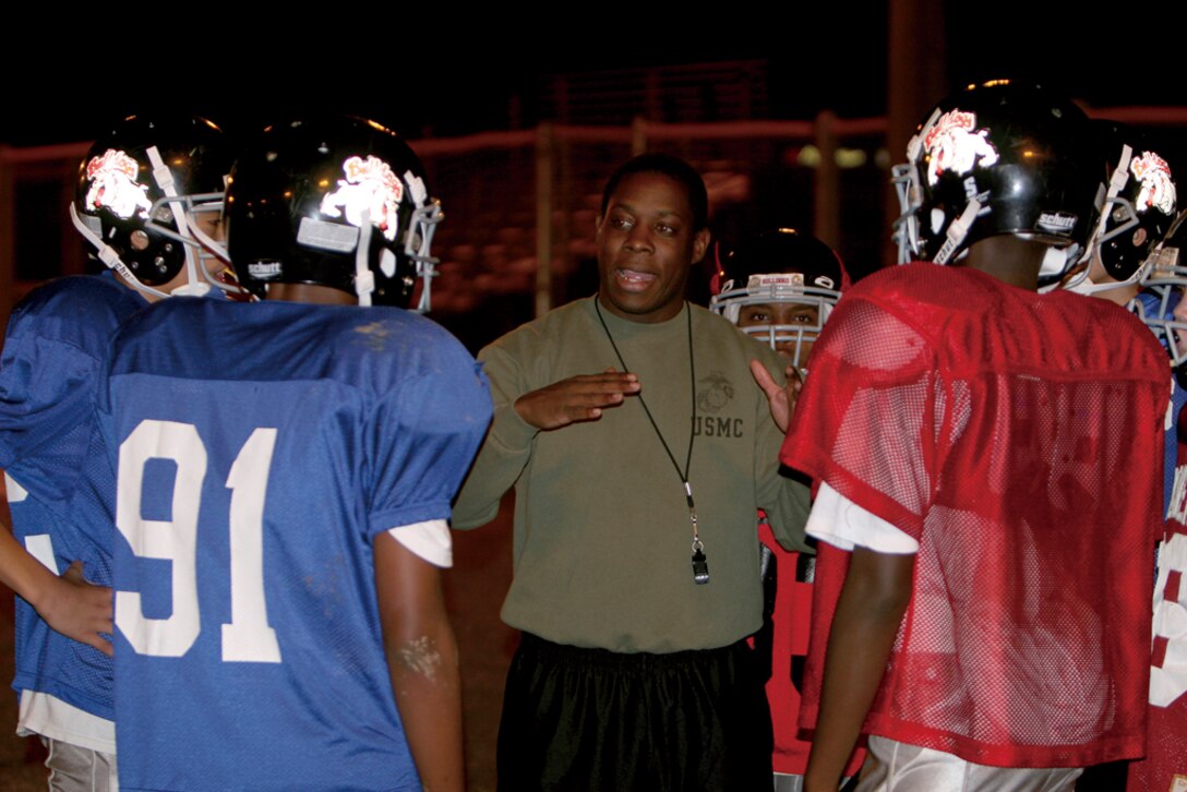 Gunnery Sgt. Harold Rolle, volunteer coach and Area Control Center chief, G-6, Marine Corps Base Camp Butler, uses coaching to provide guidance and mentorship to members of the Camp Foster Bulldogs youth football team, Nov. 15.