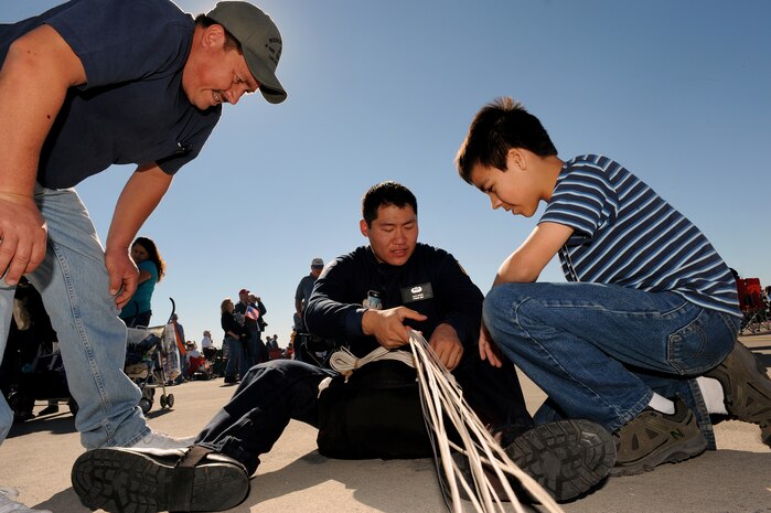 NELLIS AIR FORCE BASE, Nev. -- U.S. Air Force Academy Cadet 1st Class Alan Wong with the U.S. Air Force Academy parachute team, Wings of Blue, demonstrates how to pack a parachute to Mario and David Rodriguez during the 2010 Aviation Nation Nellis Open House Nov. 13. The Nellis Open House is an opportunity for the Las Vegas community to view aerial demonstrations and static displays of various aircraft from the military. The open house also acts as the final air show of the year for the  U.S. Air Force Air Demonstration Squadron "Thunderbirds." (U.S. Air Force photo by Senior Airman Brett Clashman)(Released)