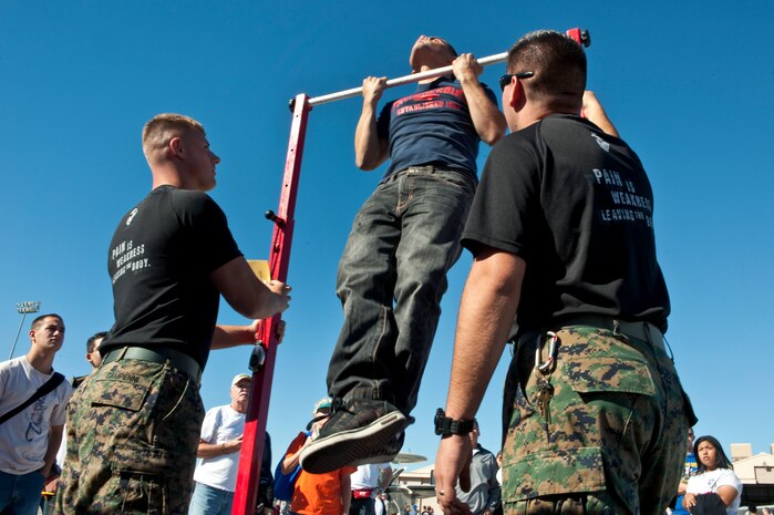 NELLIS AIR FORCE BASE, Nev. --  U.S. Marine Corps Recruiters, Sergeant's. Nicholas Campenni and Sergio Pineda encourage 18-year-old University of Arizona, student Dan Sandoval while he does pull-up's at the Marine Corps recruiting display during the 2010 Aviation Nation Nellis Open House Nov. 13. The  Open House at Nellis Air Force Base is the largest free public event in Nevada which provides the opportunity for the Las Vegas community to view aerial demonstrations and static displays of various aircraft from the military. The open house also acts as the final air show of the year for the  U.S. Air Force Air Demonstration Squadron "Thunderbirds." (U.S. Air Force photo by Tech. Sgt. Michael R. Holzworth)(Released)
