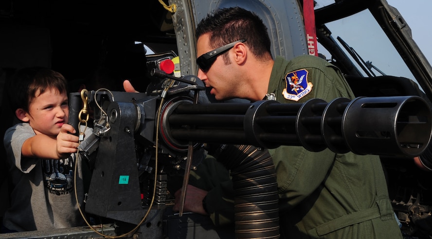MOODY AIR FORCE BASE, Ga.-- Staff Sgt. Justin Martin, 41st Rescue Squadron aerial gunner, explains to Frank Tucker, son of Kristen Pinburthe and Frank Tucker, how the 7.62mm minigun is used. The HH-60G Pave Hawk was one of the static displayed at the Moody  Community Appreciation Day Air Show. (U.S. Air Force photo/Senior Airman Stephanie Longoria)(RELEASED)