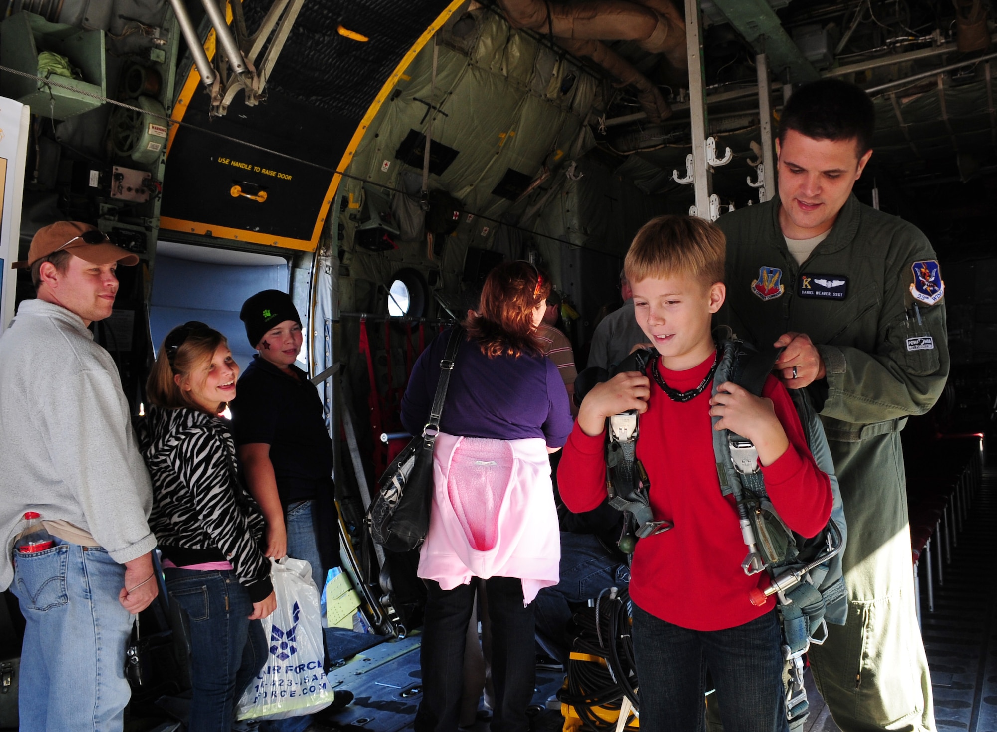 MOODY AIR FORCE BASE, Ga.-- Staff Sgt. Daniel Weave, 71st Rescue Squadron airborne mission systems specialist, helps John Maples, son of Lesley and Lawanna Maples, try on a parachute used on the HC-130 Combat King Nov. 13. Thousands of people from the local community came out to watch the  Community Appreciation Day Air Show. (U.S. Air Force photo/ Senior Airman Stephanie Longoria)(RELEASED)