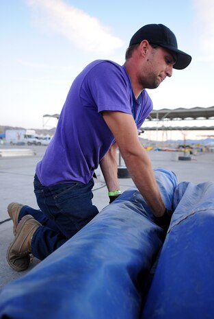 NELLIS AIR FORCE BASE, Nev.--  Kyle Flint packs away an inflatable jumper castle as the 2010 Aviation Nation Nellis Open House comes to a close Nov. 14. The Nellis Open House was an opportunity for the Las Vegas community to view aerial demonstrations and static displays of various aircraft from the military. The open house also acts as the final air show of the year for the U.S. Air Force Air Demonstration Squadron, "Thunderbirds." (U.S Air Force Photo / Airman 1st Class Matthew Lancaster) (Released)