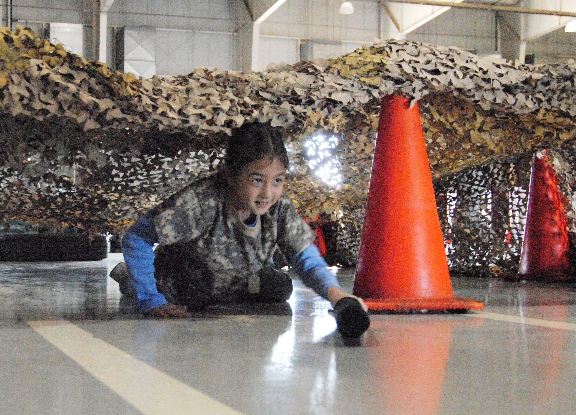 GOODFELLOW AIR FORCE BASE, Texas -- Katie Lieberman, 8, crawls through the Marine Corps obstacle course at the deployed air base.during Operation KIDS 2010 Nov. 13.  More than 60 military youths participated in this year's event to get a glimpse of what their military parent(s) go through when deploying.  (U.S. Air Force photo/Connie Hempel)