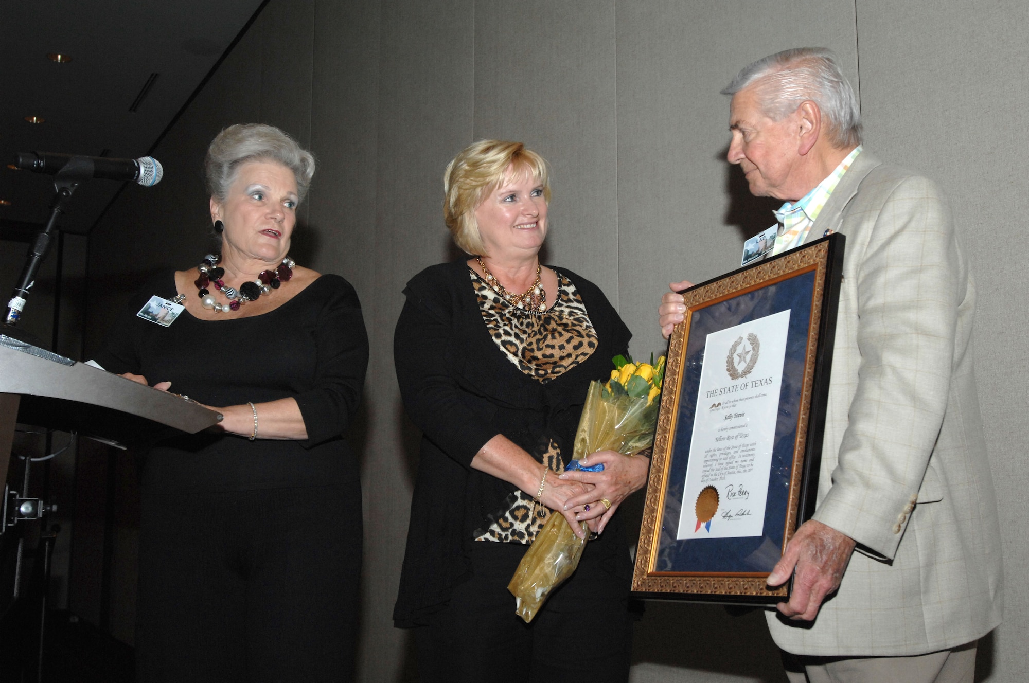 Mrs. Sally Travis, wife of Maj. Gen. Thomas Travis, 59th Medical Wing commander (center), receives the Yellow Rose of Texas award on behalf of Governor Rick Perry, from Mrs. Janice Ricks, Greater San Antonio Chamber of Commerce liaison for the 59th MDW, (left), and her husband Les Paulick (right) during her husband's farewell dinner at the Westin La Cantera Resort, San Antonio, Texas Nov. 12, 2010. The award, given only through the Office of the Governor, recognizes Texas women for significant contributions to their communities and to Texas in the preservation our Texas history, the accomplishments of our present and the building of our future. The award is named for Emily Morgan, a 20-year-old slave who was instrumental in the battle to win Texas' independence, as she gave General Sam Houston's troops Santa Anna's location. (U.S. Air Force photo/Staff Sgt. Robert Barnett)